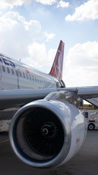 Detailed view of a jet engine and aircraft tail at an airport. Ideal for travel and aviation themes.