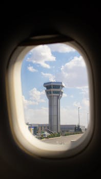 A scenic view of an air traffic control tower through an airplane window, symbolizing travel and aviation.