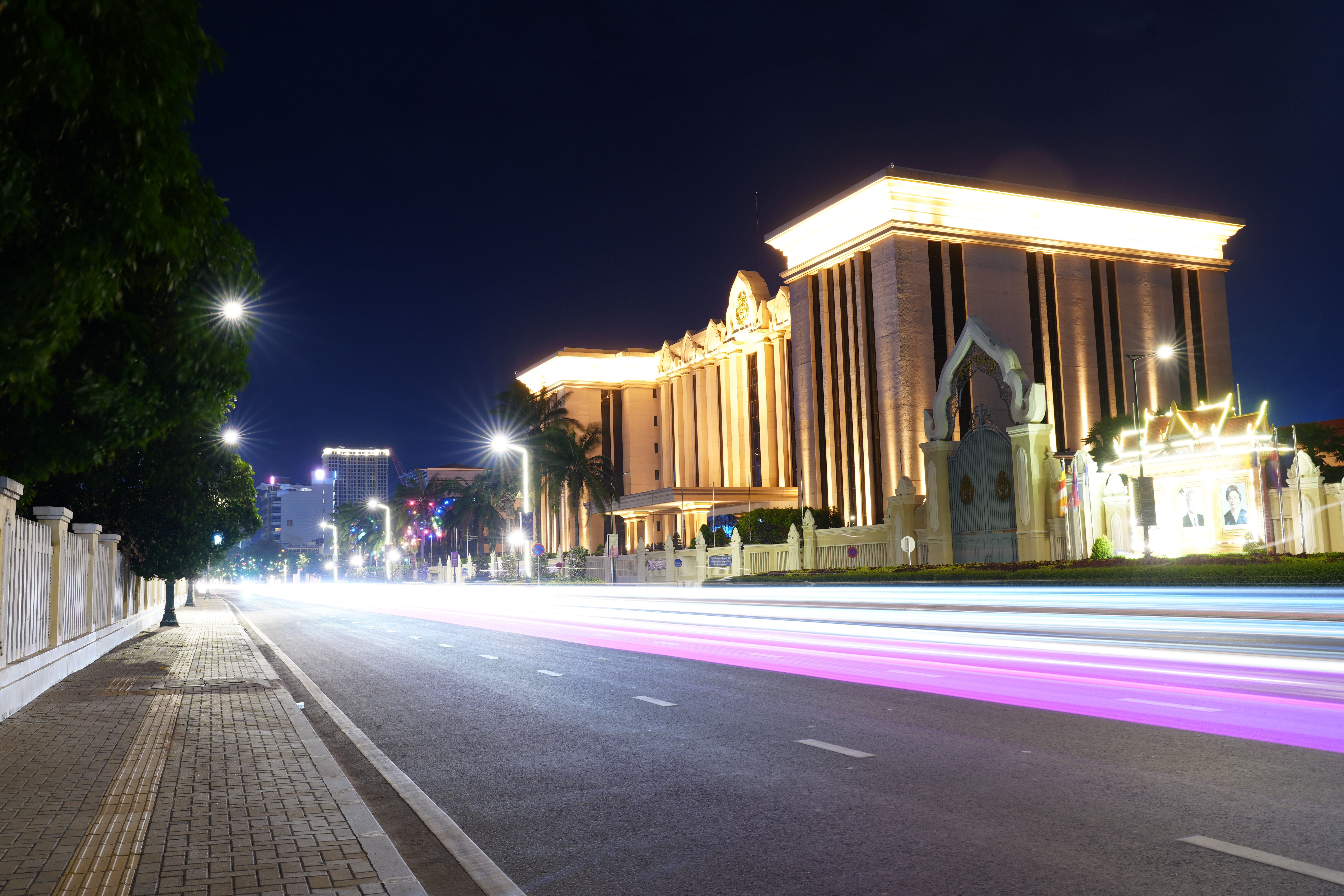 Vibrant urban street at night showcasing illuminated buildings and dynamic light trails.