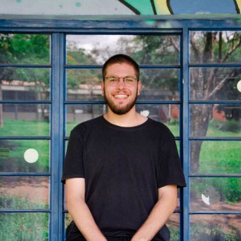 A cheerful young man smiling against a vibrant mural outdoors