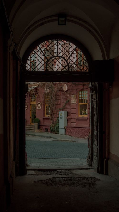 Free Street view through an archway in historic Chernivtsi, showcasing classic architecture. Stock Photo