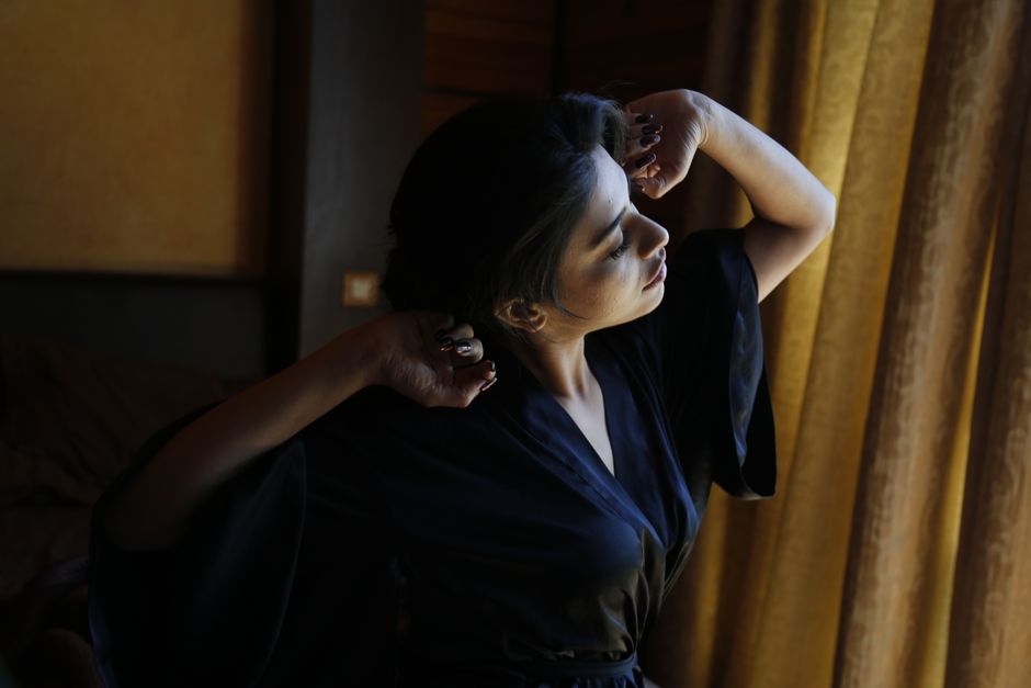 A woman stretching by a window, bathed in soft morning light, creating a peaceful bedroom scene.