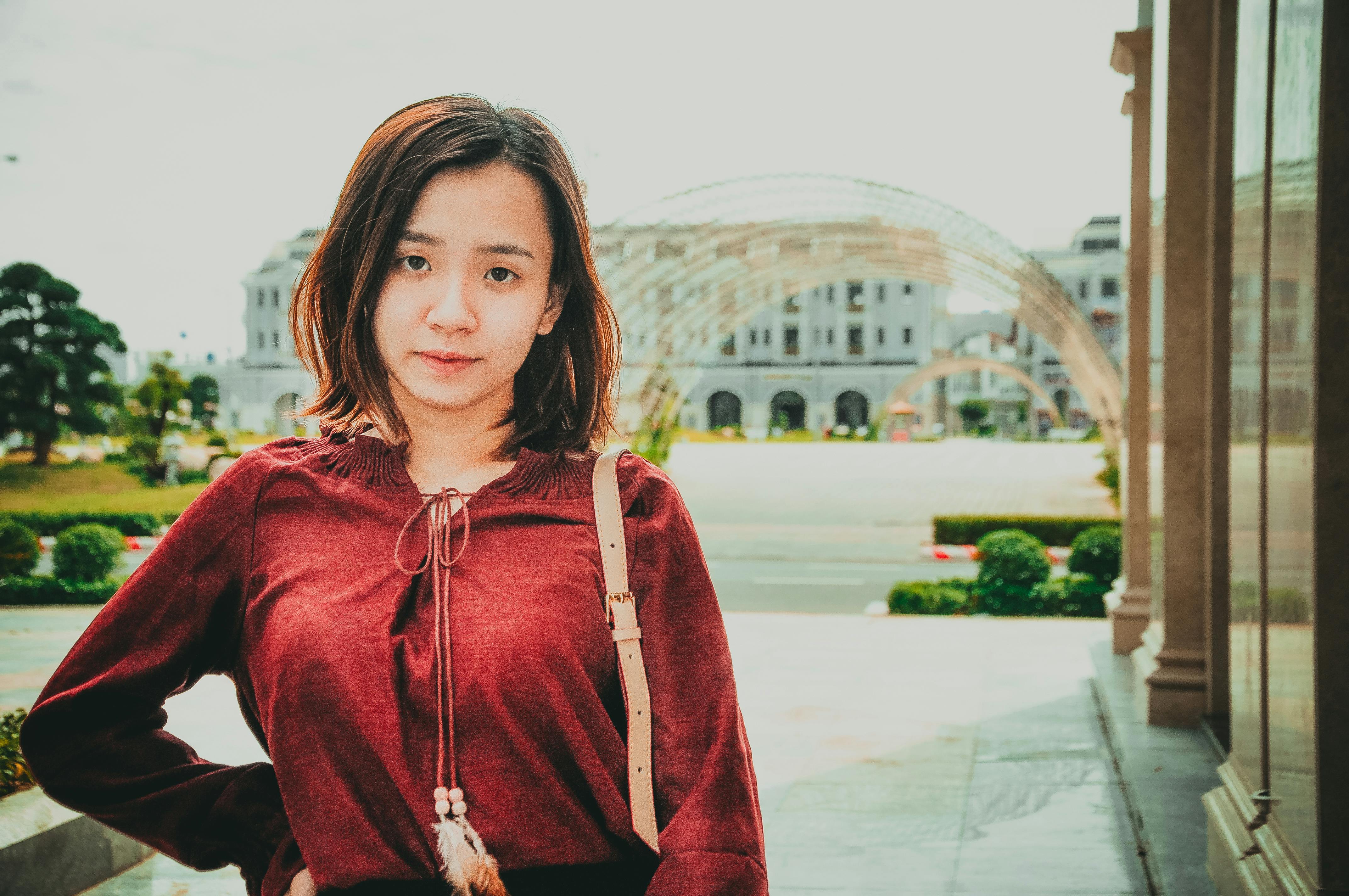一位身穿红色上衣的亚洲年轻女子在户外拍摄的肖像，散发着宁静的气息