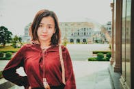 一位身穿红色上衣的亚洲年轻女子在户外拍摄的肖像，散发着宁静的气息