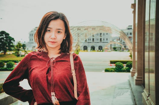 一位身穿红色上衣的亚洲年轻女子在户外拍摄的肖像，散发着宁静的气息