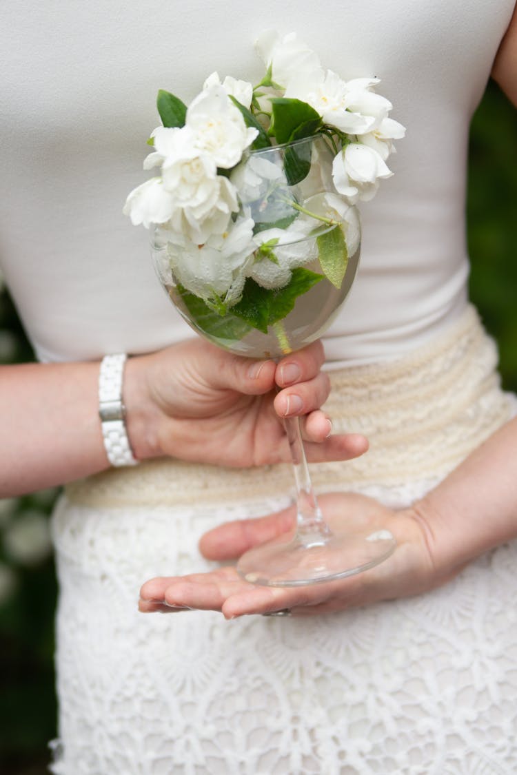 Woman Hands Holding Glass With White Flowers