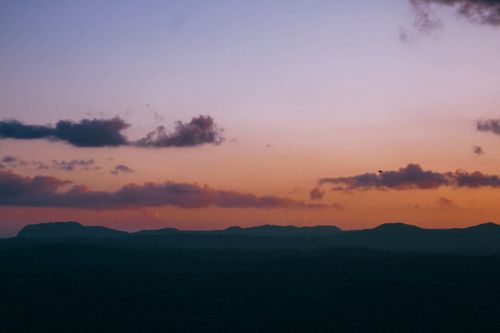 Free A tranquil sunset over mountains with colorful sky and silhouette of clouds. Stock Photo