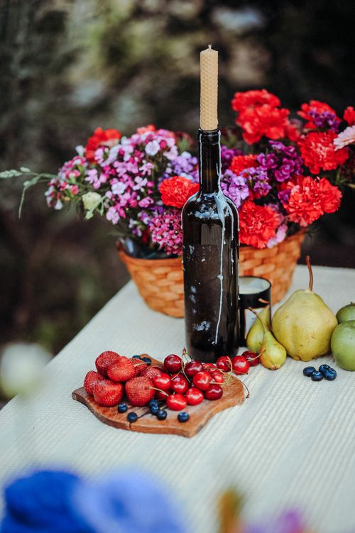 Free Vibrant display of fruits, flowers, and a wine bottle on a table. Stock Photo