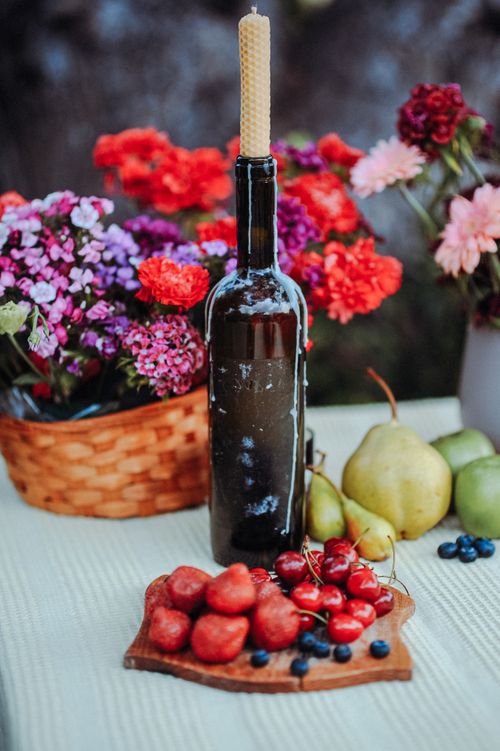 Free Vibrant still life featuring colorful flowers, fresh fruit, and a bottle with a wax candle. Stock Photo