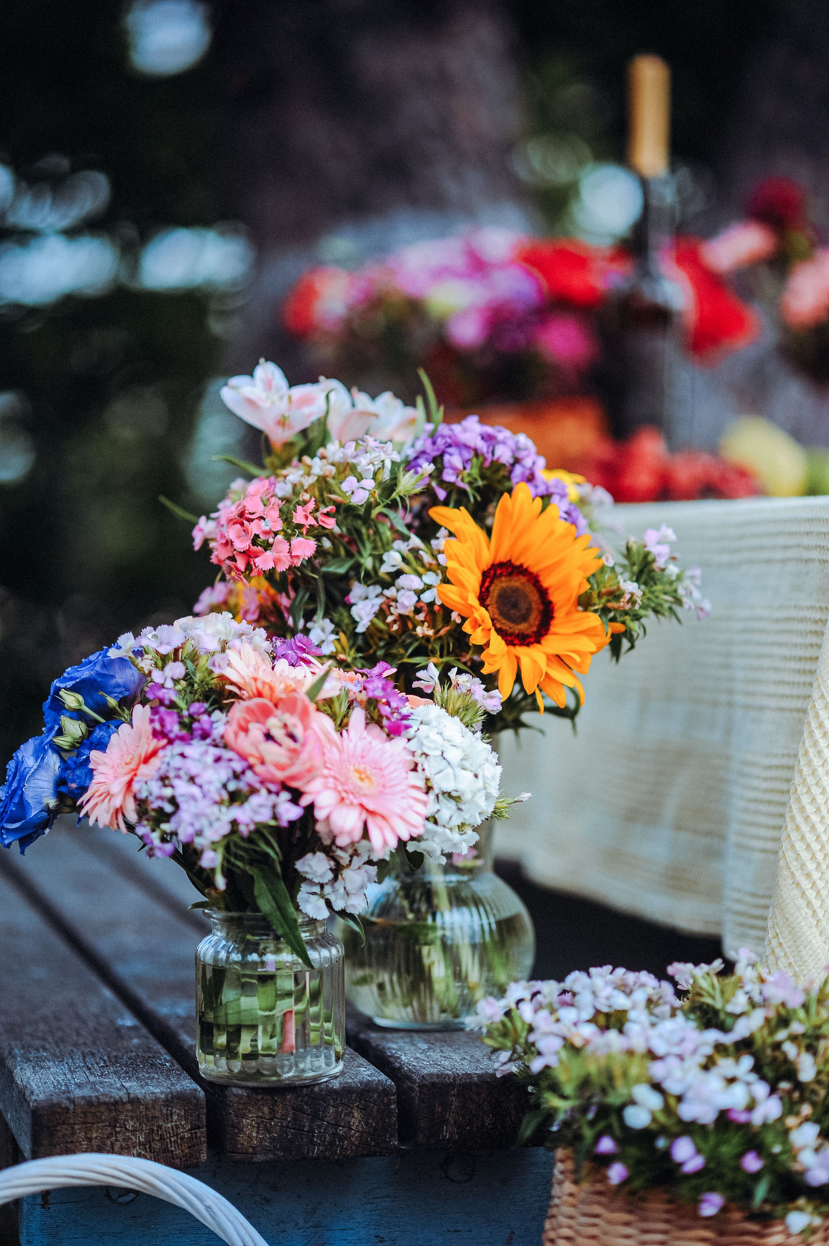 [ColoSach]-colorful-flower-bouquets-in-glass-vases-on-an-outdoor-wooden-table,-creating-a-vibrant-and-natural-decor-setting.