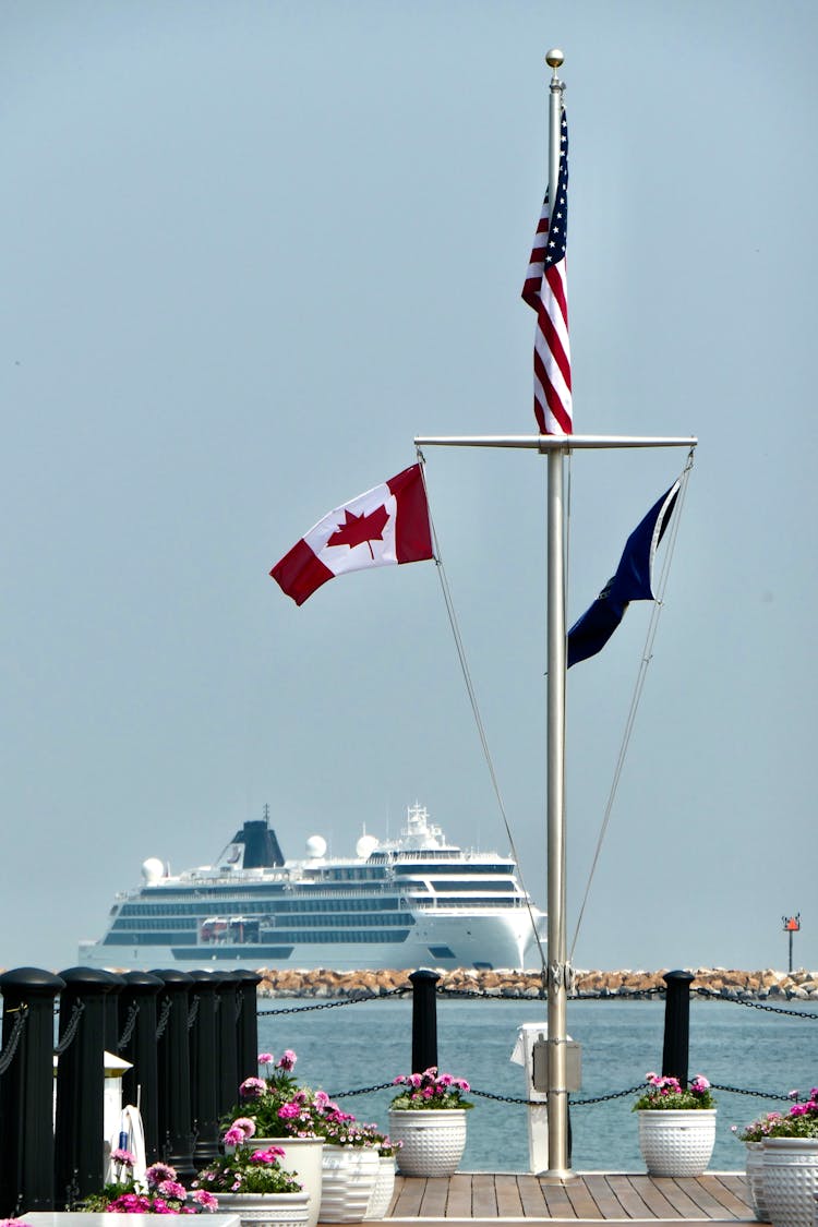 Cruise Ship Behind Canadian And American Flags On Shore