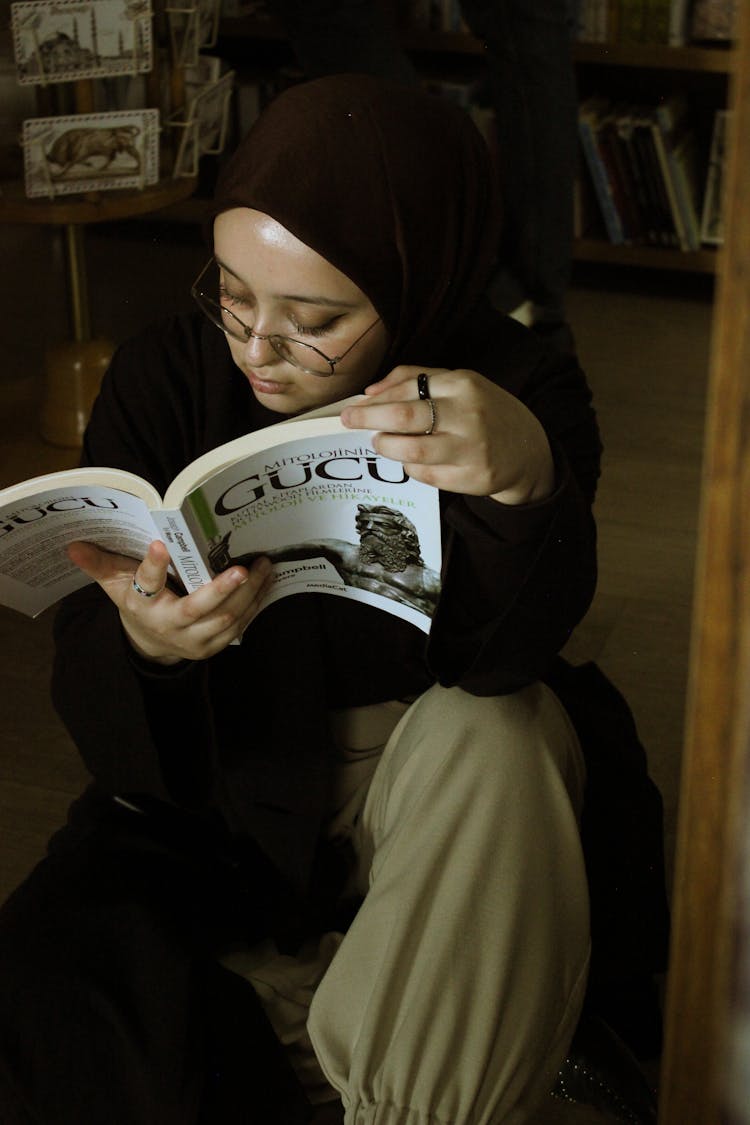 Woman In Eyeglasses Sitting And Reading Book