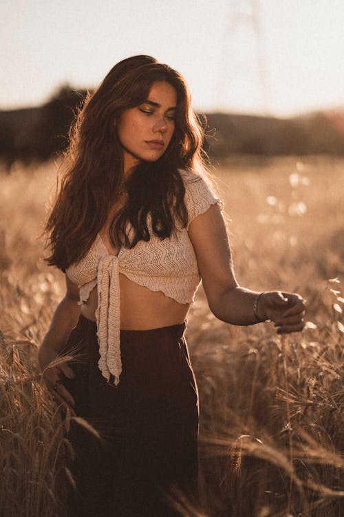 Young Brunette Posing on a Field in Summer at Sunset