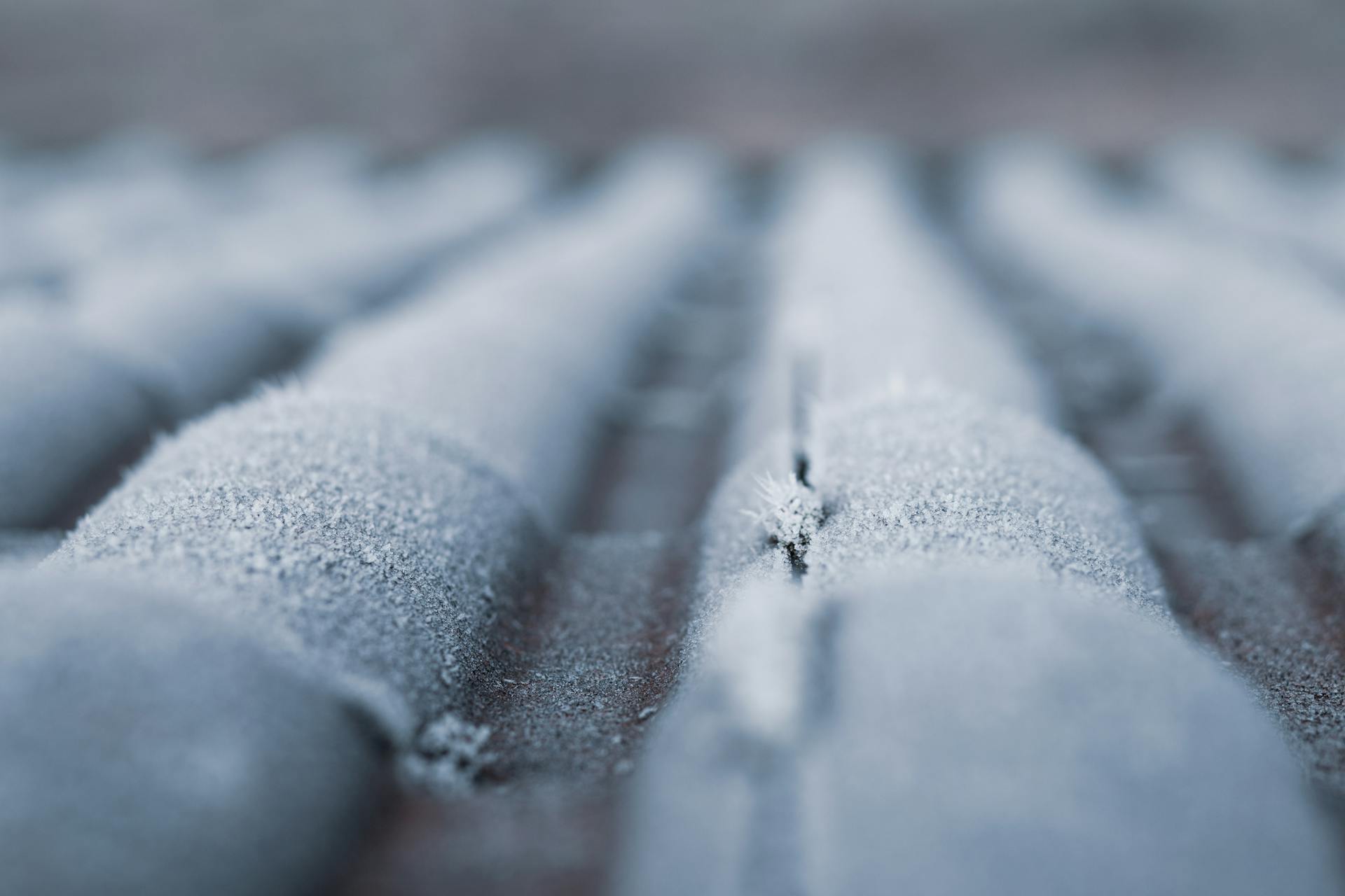 Detailed view of frosty roof tiles showcasing winter's icy texture and cold weather effect.