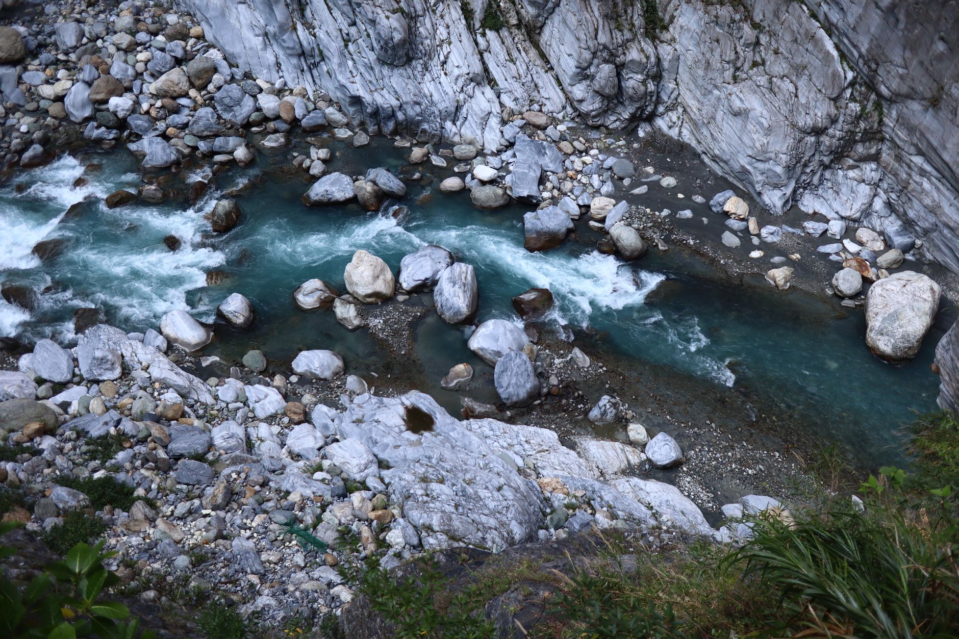 Aerial view of blue river flowing through rocky gorge in Hualien, Taiwan, showcasing nature's beauty.