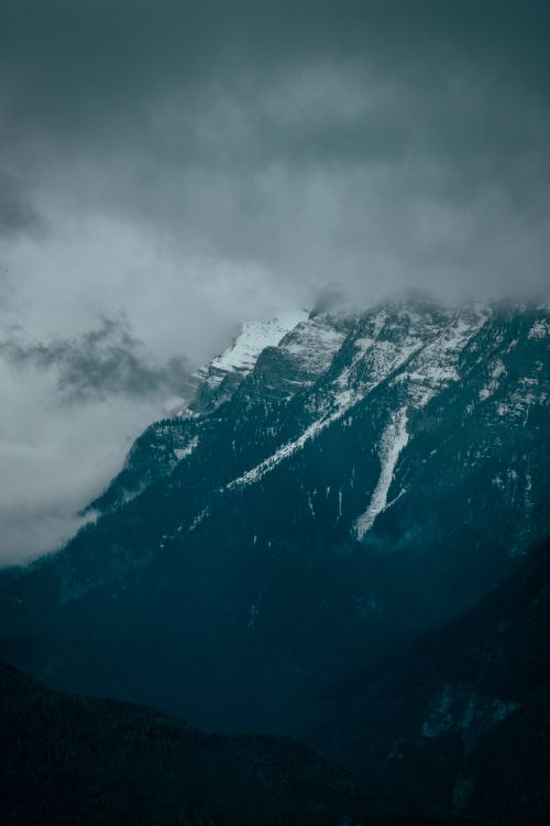 Free A dramatic view of snowy mountain peaks shrouded in mist and clouds, capturing the mysterious beauty of nature. Stock Photo