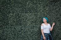 Woman in White Top Standing in Front of Green Leafed Hedge Wall