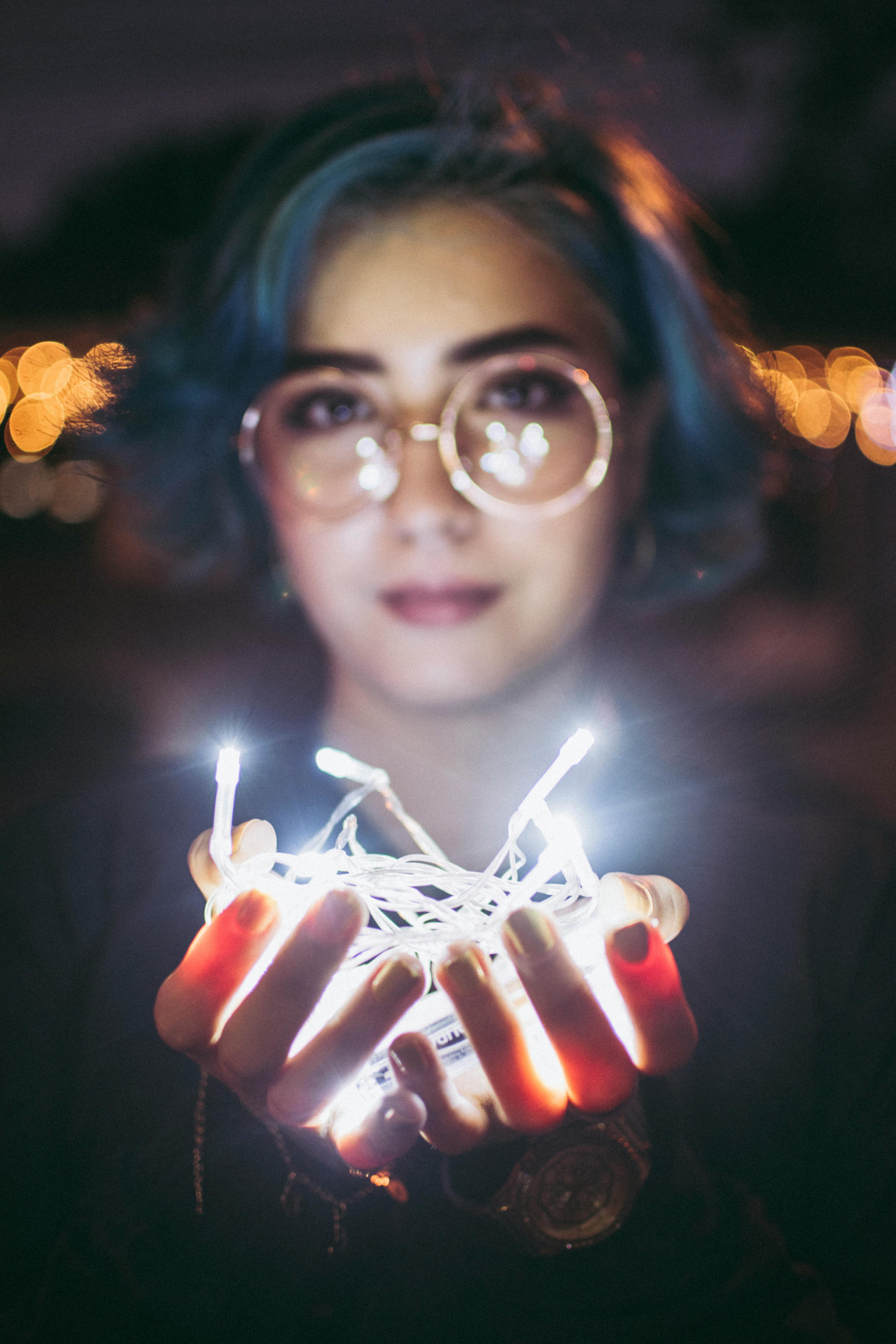 晚上，一名蓝发女子手持发光的串灯