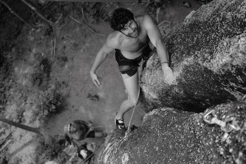 Free Man climbing a rock face, showcasing strength and determination. A thrilling outdoor adventure captured in black and white. Stock Photo