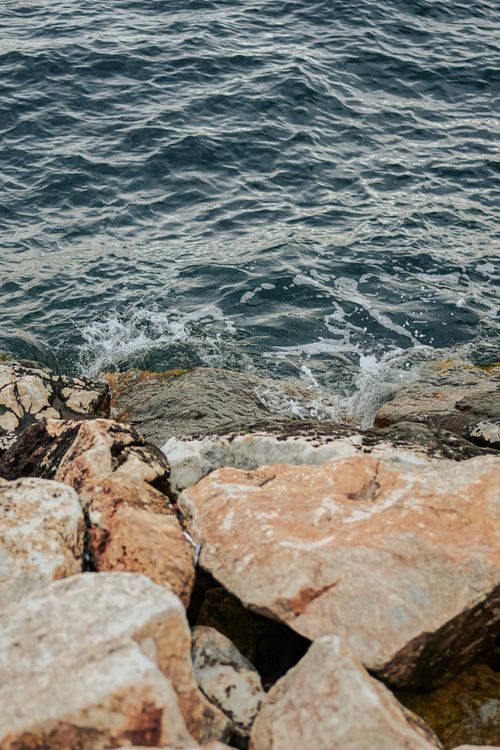 Free Eroded coastal rocks with crashing ocean waves create a serene natural seascape. Stock Photo