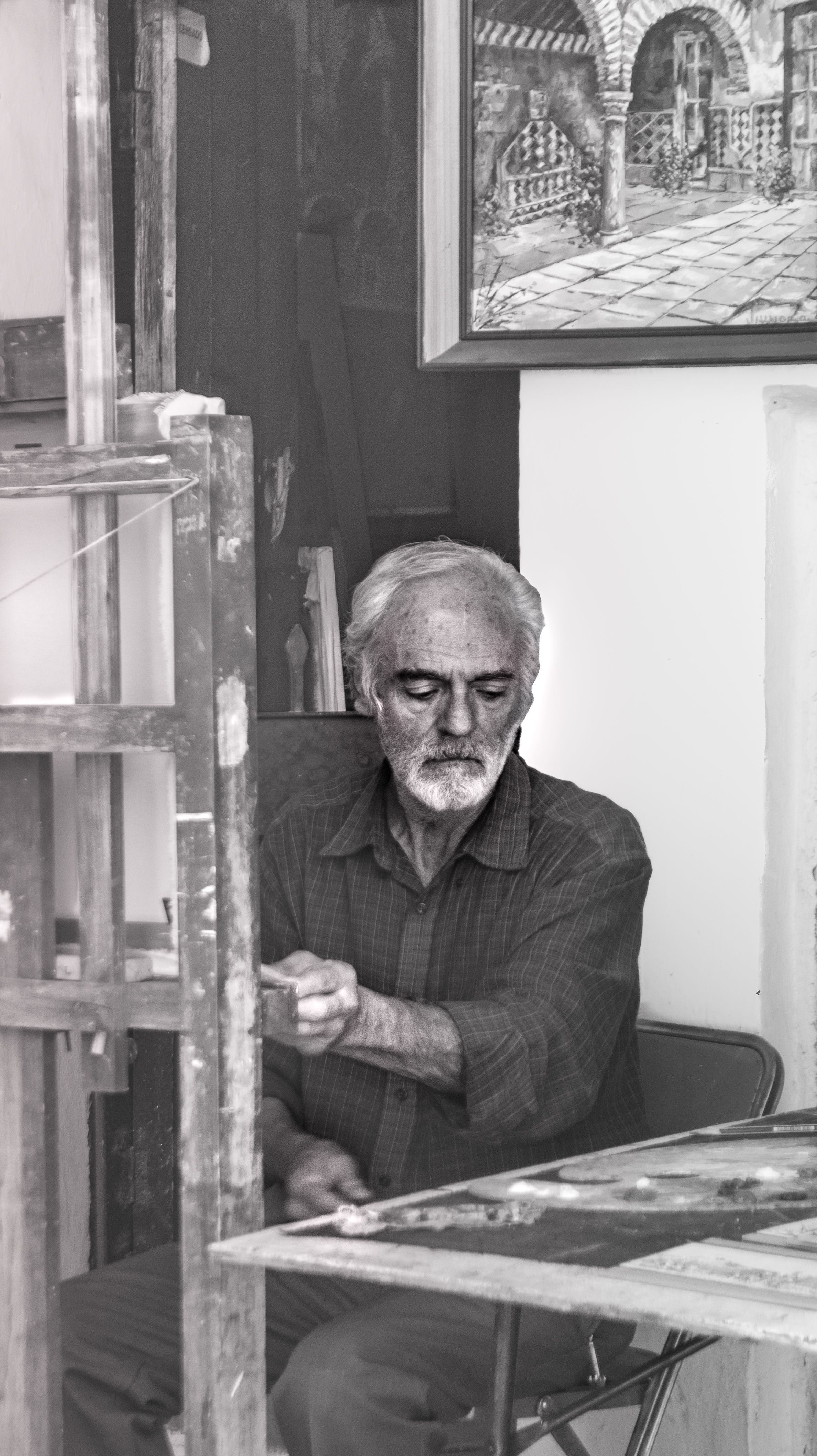 Elderly man sitting in a Puebla studio, engaged in thoughtful creativity.