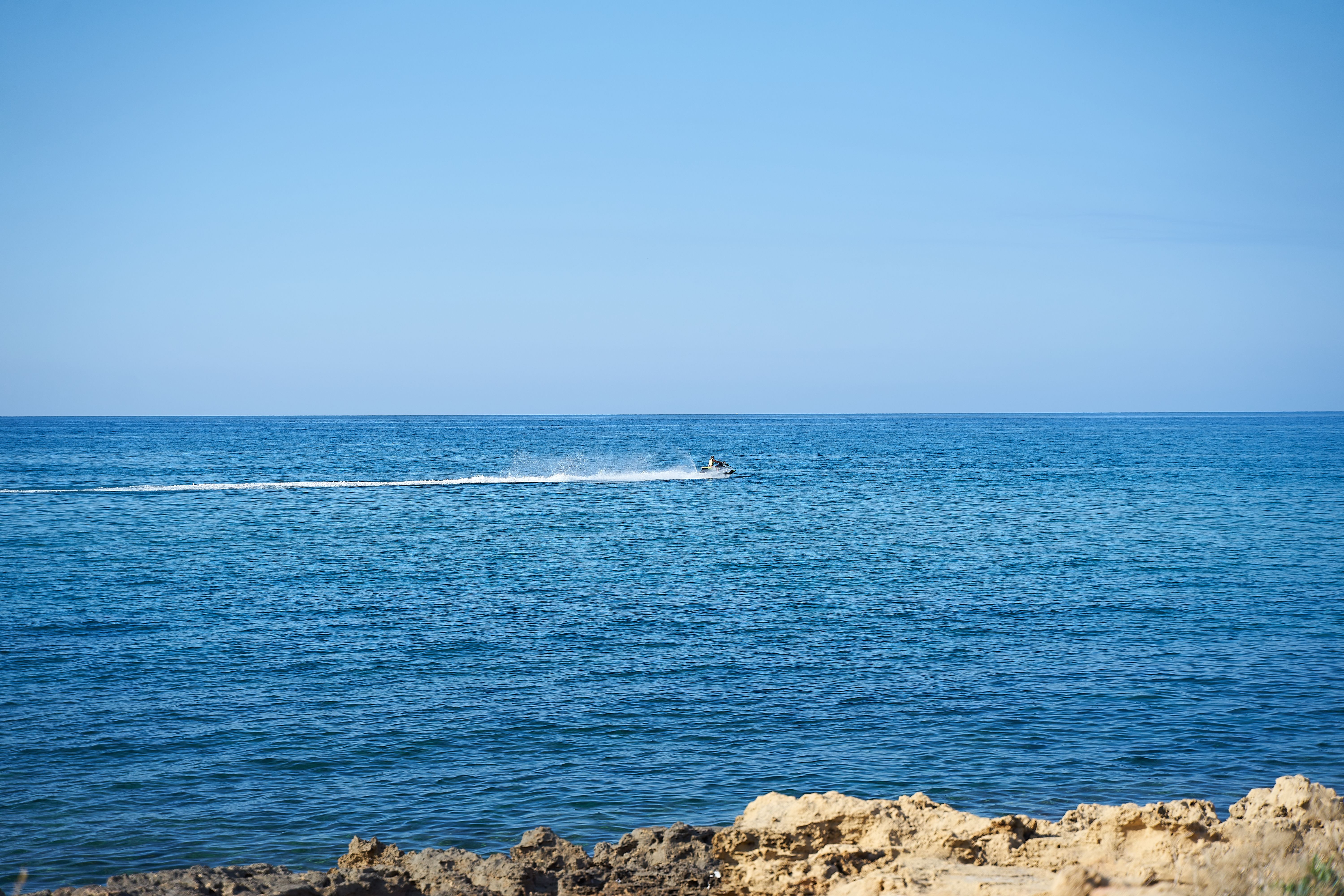 A thrilling jet ski ride across the open sea under a clear blue sky.