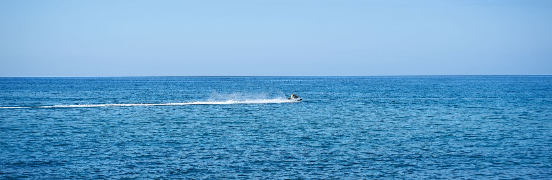 A thrilling jet ski ride across the open sea under a clear blue sky.