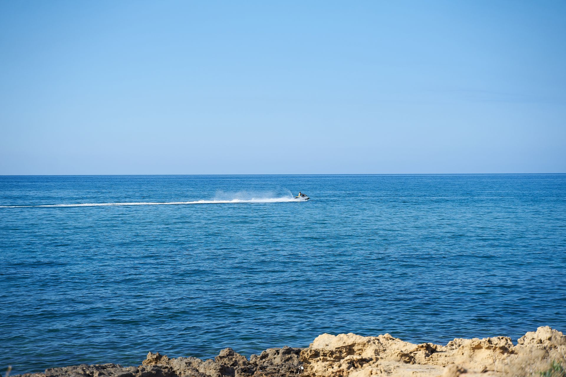 A thrilling jet ski ride across the open sea under a clear blue sky.