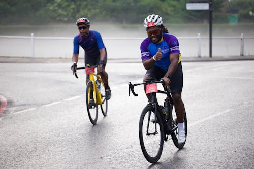 Two men riding bicycles on a rainy day