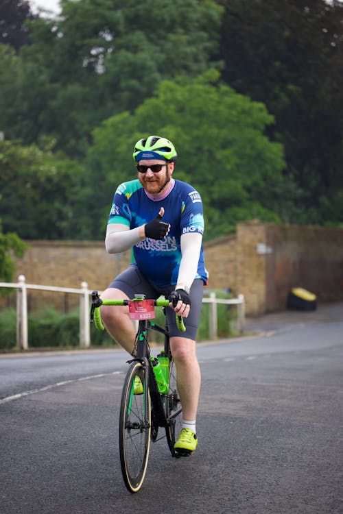 A man in a green shirt and blue helmet riding a bike