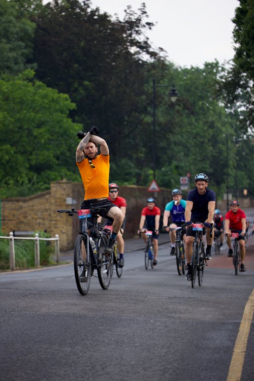 A man in an orange shirt is riding a bike