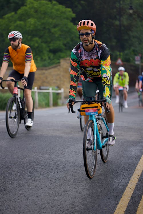 A man in an orange shirt is riding a bike