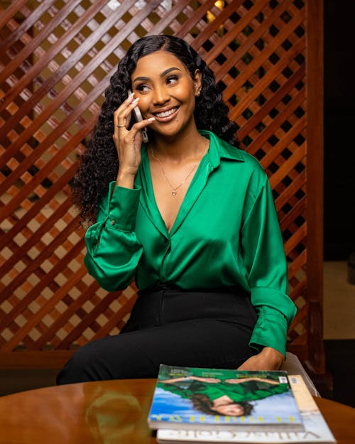 Young Woman in a Green Shirt Talking on the Phone and Smiling 