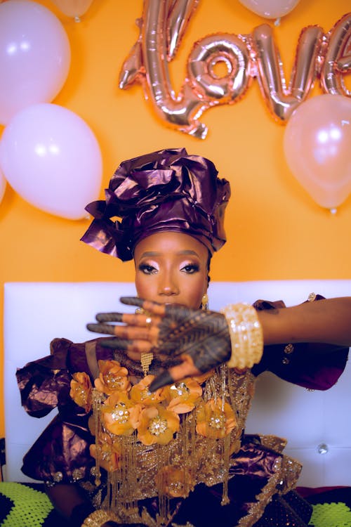 Young Woman in Traditional Clothing Sitting on the Background of a Wall with Balloons 