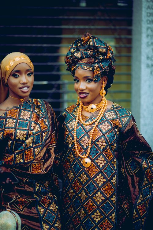 Free Two African women wearing colorful traditional dresses and headscarves, smiling outdoors. Stock Photo