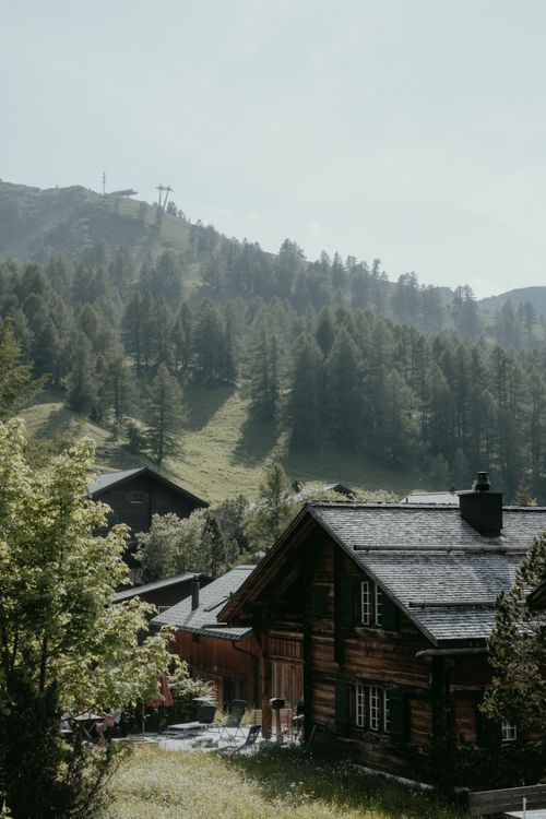 Free Scenic view of traditional wooden houses in Malbun, surrounded by lush forests and hills. Stock Photo