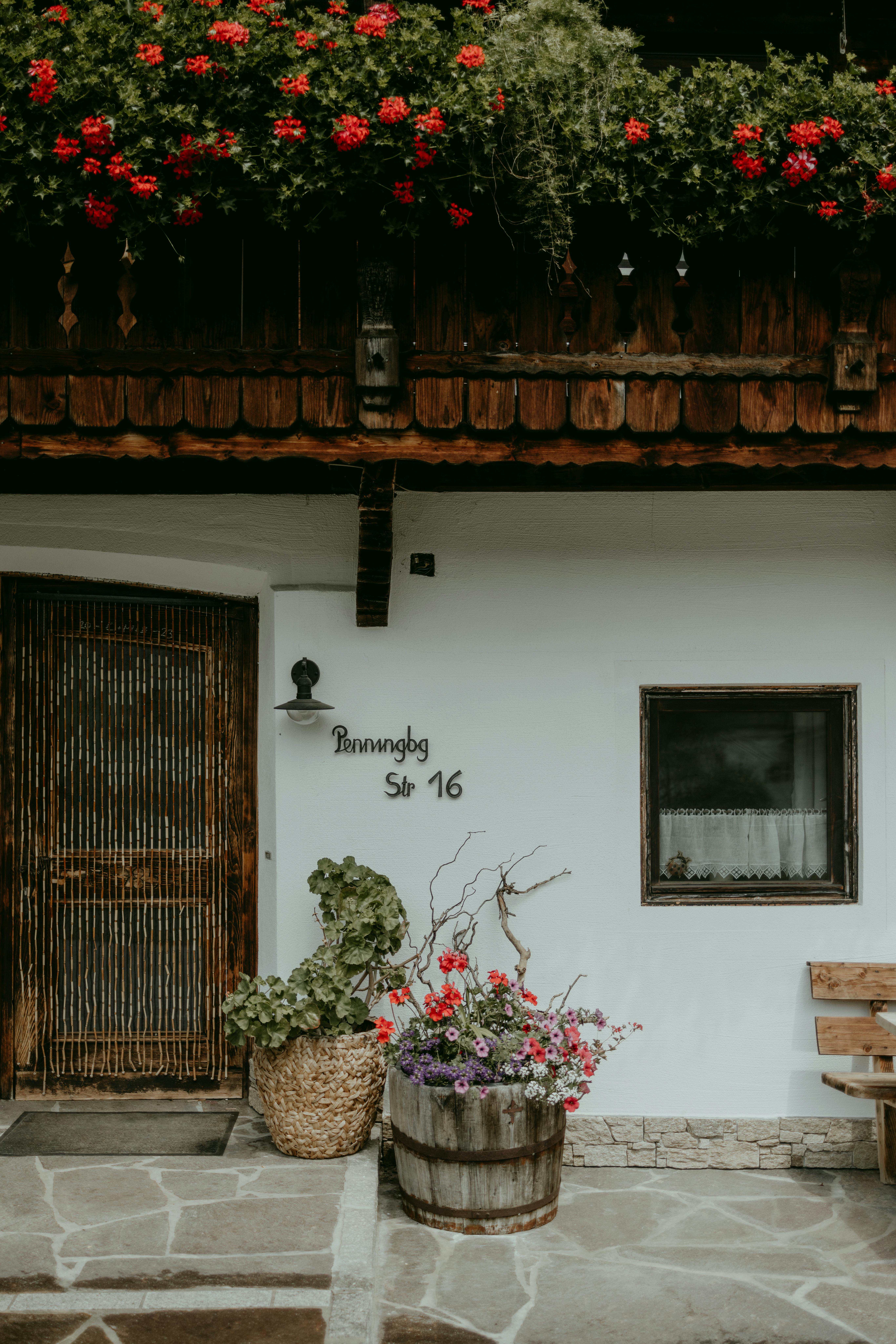 A picturesque rustic house entrance adorned with vibrant flowers in a wooden barrel.