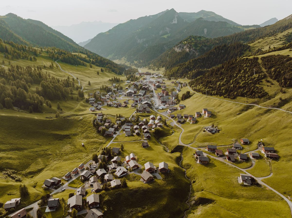 Satul Malbun văzut din dronă, cu chalete grupate pe pajiștile alpine