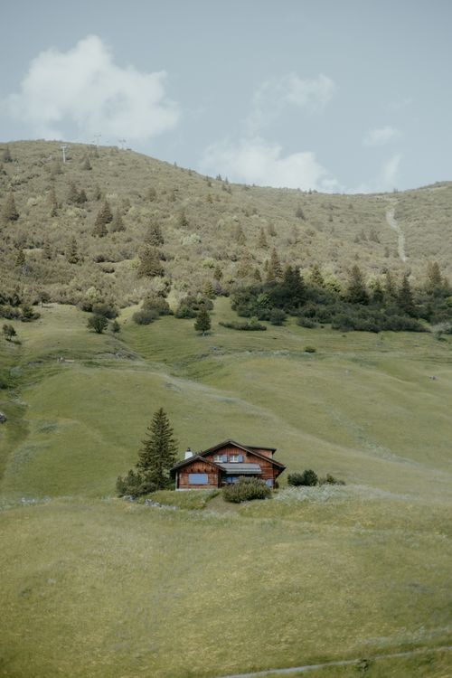 Free Charming wooden cabin nestled in the tranquil hills of Malbun, showcasing pristine alpine scenery under a clear sky. Stock Photo