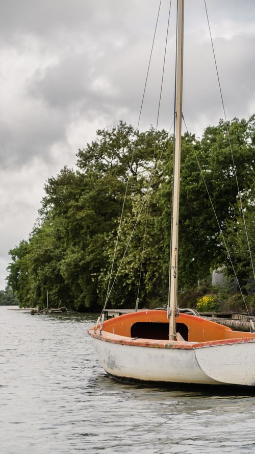 Free Tranquil scene of a sailboat on a river in Carbonne, Occitanie, France, surrounded by lush greenery. Stock Photo
