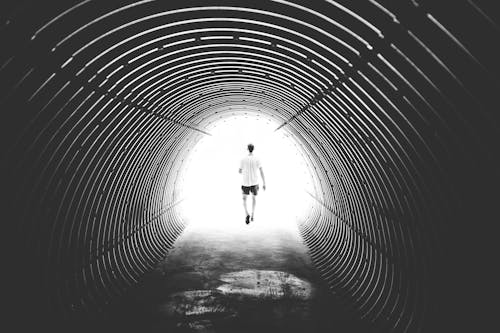 Grayscale Photo of Man Walking in Hole