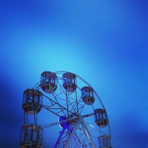 Ferris Wheel with Empty Cabins against Blue Evening Sky