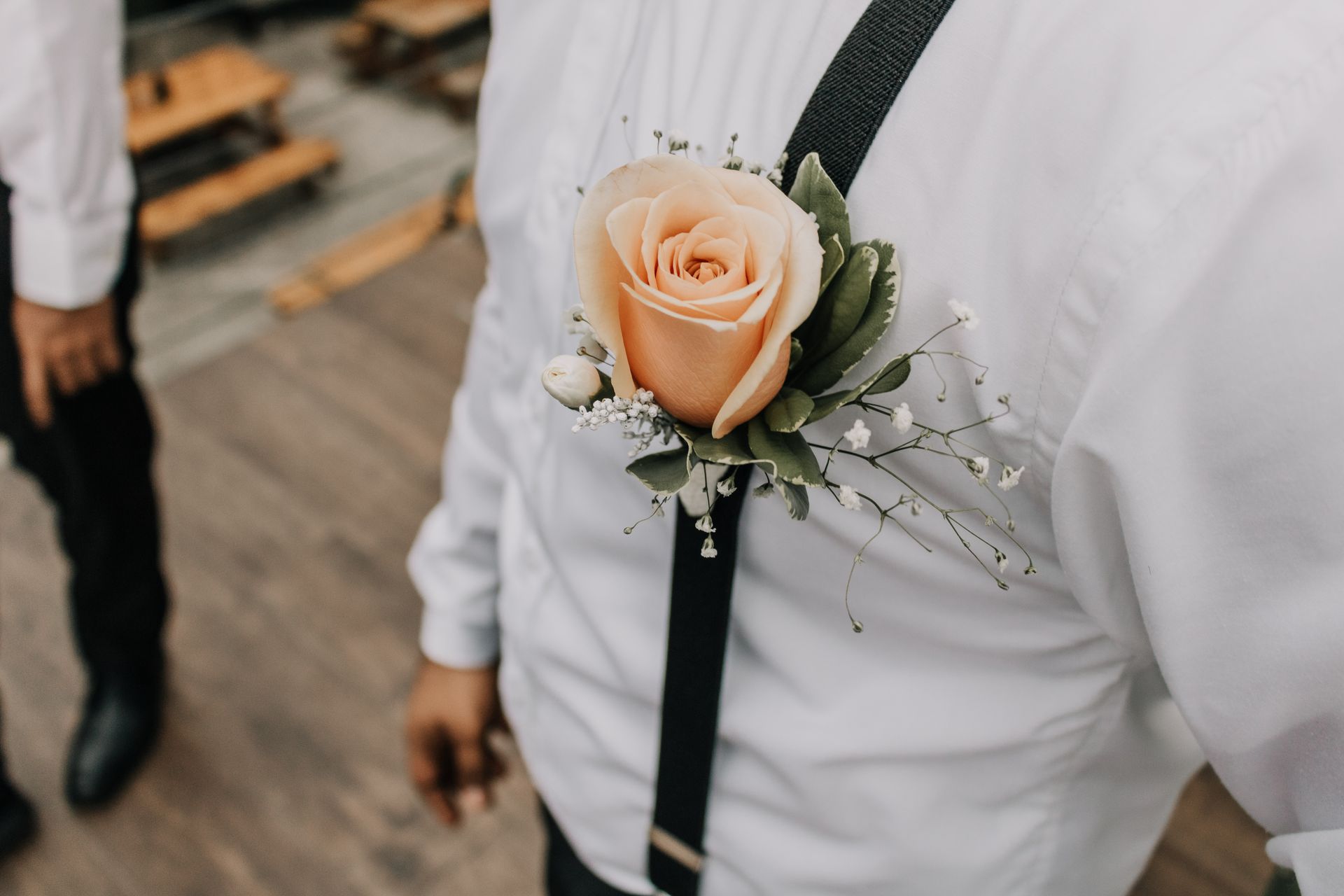 Close-up of a peach rose boutonniere on a groom's lapel, perfect for weddings.
