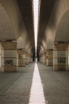 Symmetrical view under Pont del Regne in Valencia, showcasing its arches and modern urban design.