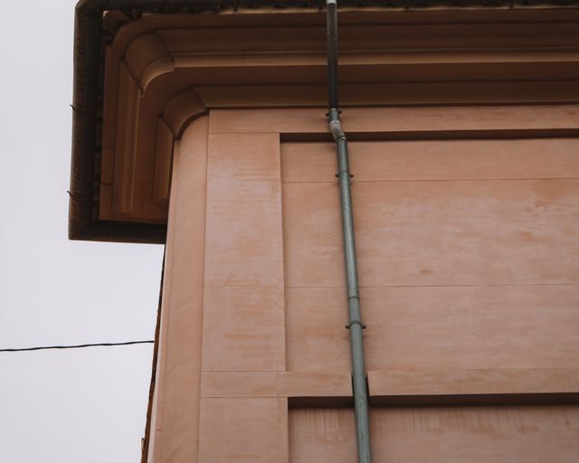 Gutter and downspout on a home Corner of a home with a metal gutter and downspout against a wall