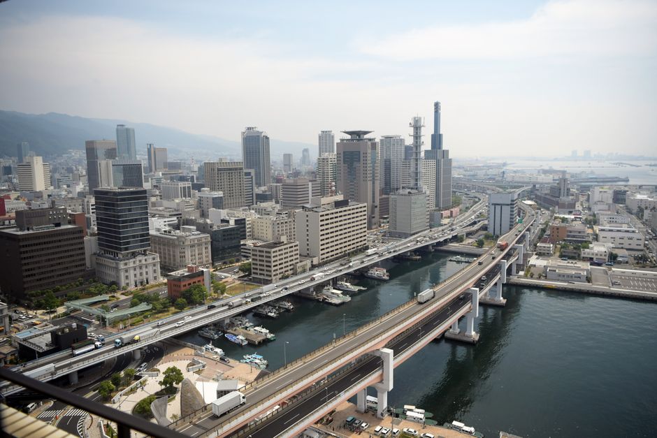 High-angle view of Kobe city skyline with bridges over the river, showcasing modern skyscrapers and urban landscape.