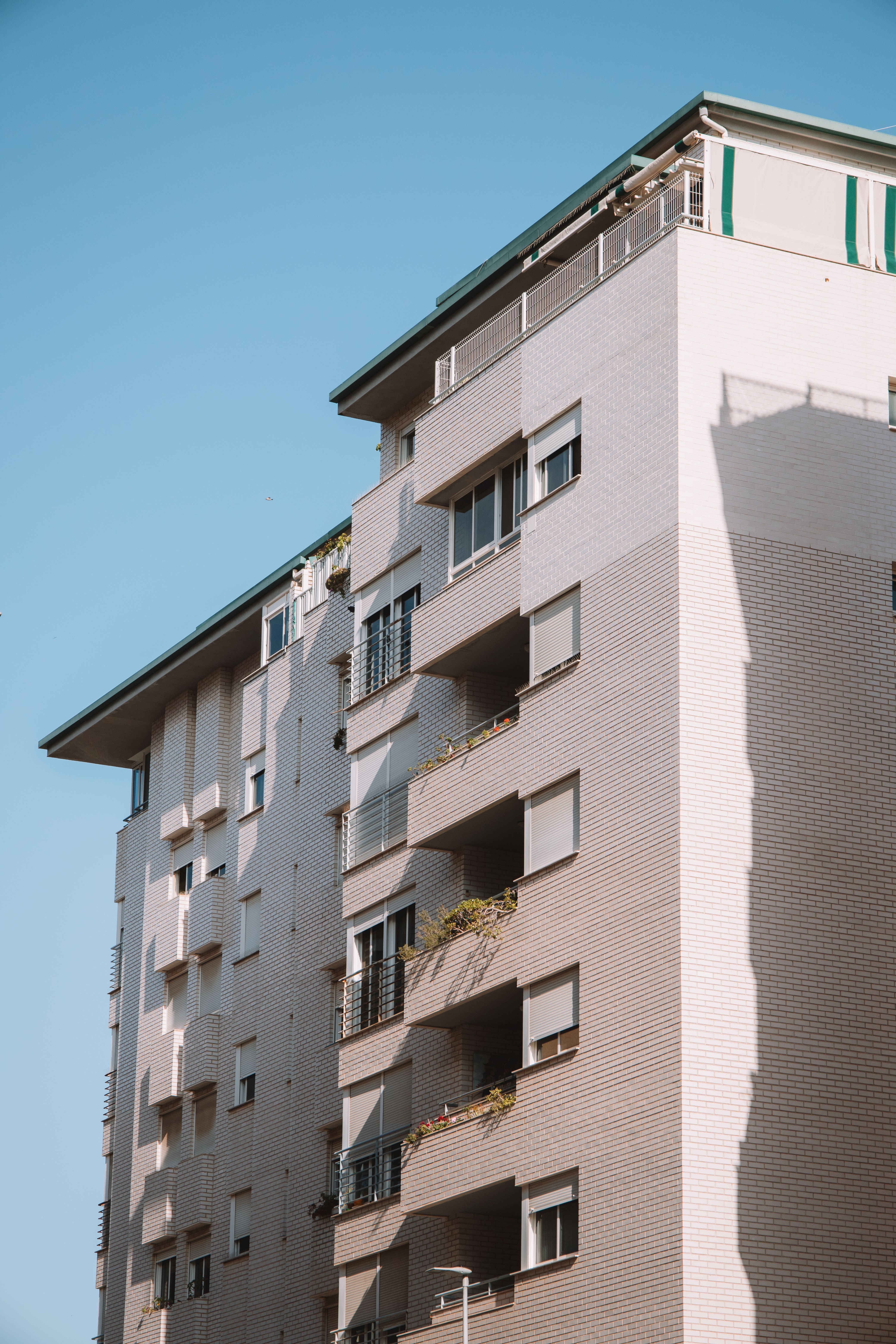 A contemporary residential building with balconies under a clear blue sky.