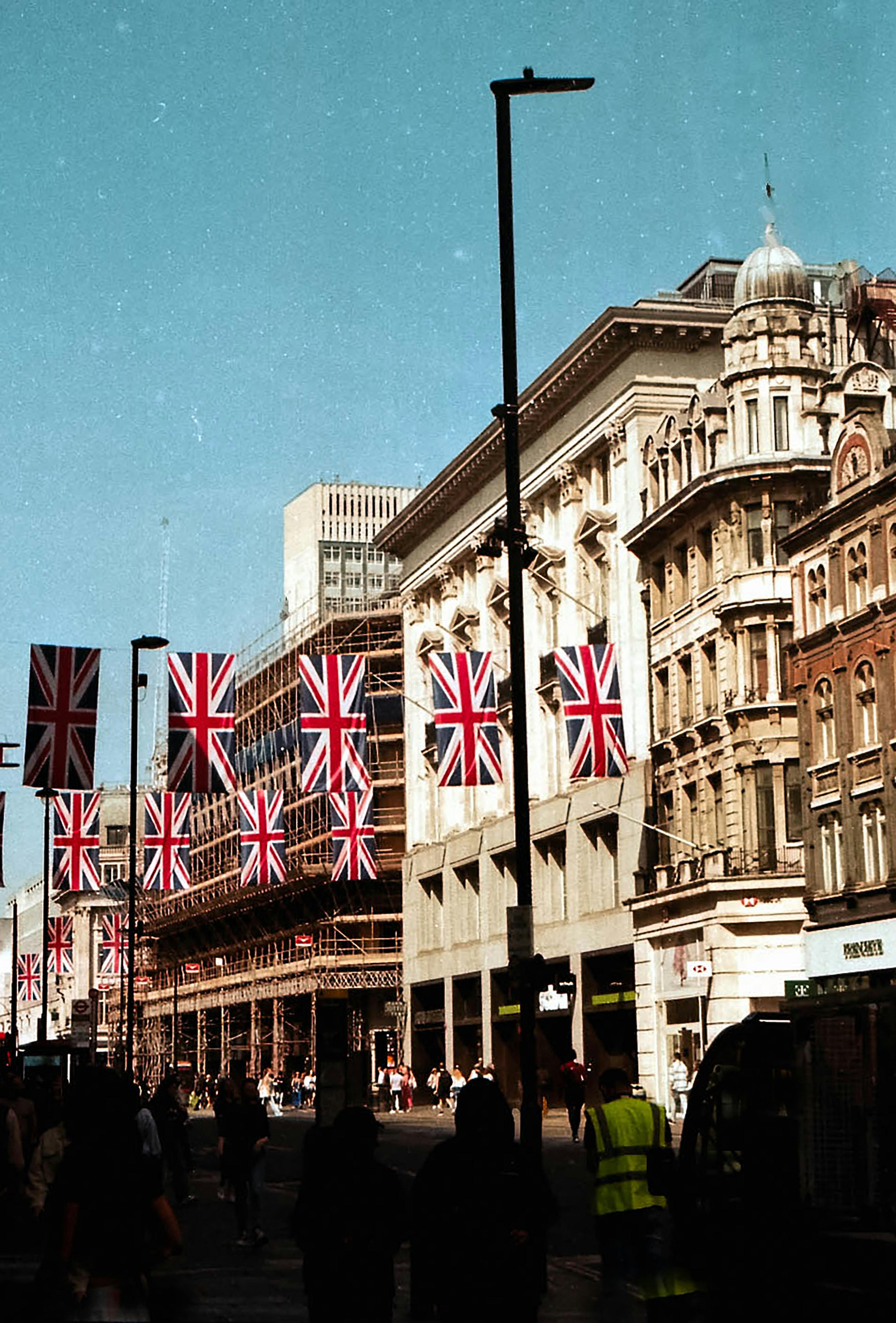 Lively London street with Union Jack flags under a clear blue sky and traditional architecture.