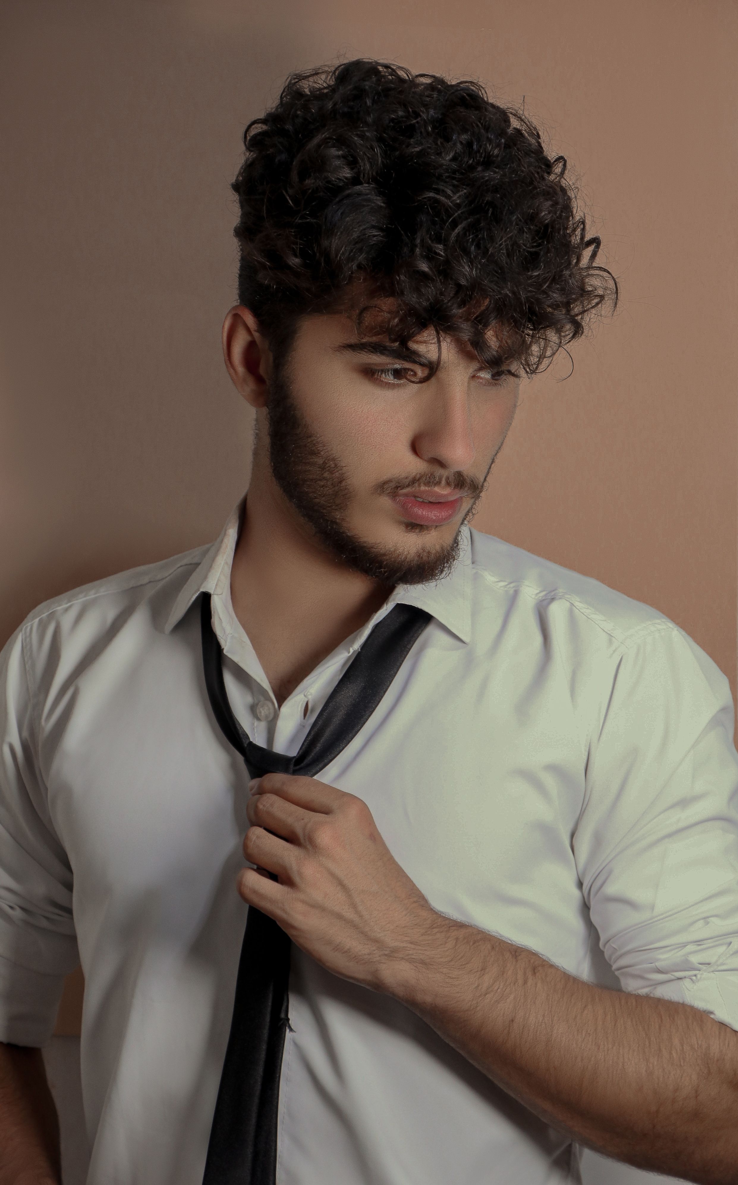 Hair products for men with curly hair styled into defined coils on a confident young man