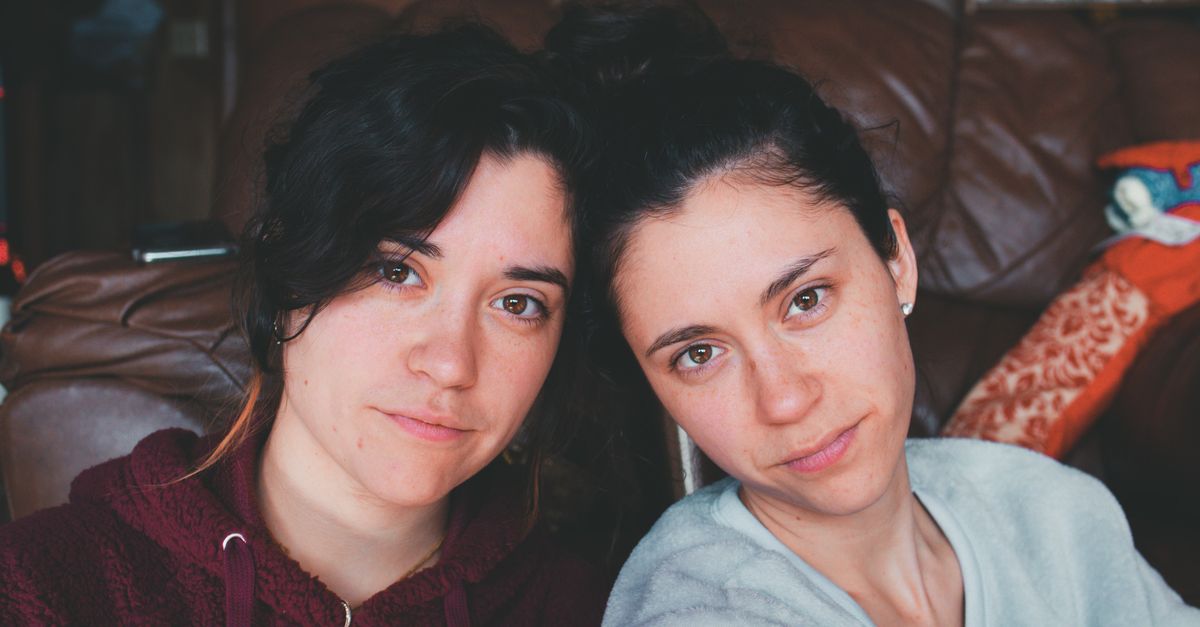 A candid indoor portrait of two sisters with natural expressions and cozy outfits.